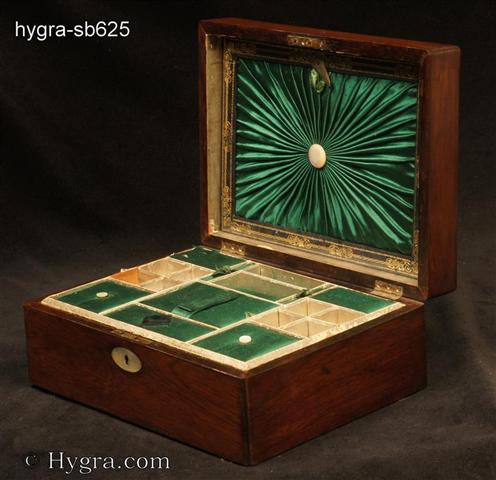 Ref:  SB625: Rosewood sewing box with mother of pearl oval inlaid to the top and rounded edges  retaining its original  compartmentalized tray with supplementary lids in green satin silk. There is a document wallet in the lid.  This has ruched green satin silk framed with gold embossed leather.  The box has a working lock with key, Circa 1850  Enlarge Picture